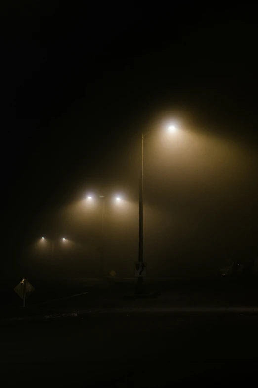 foggy street lights in front of a road sign