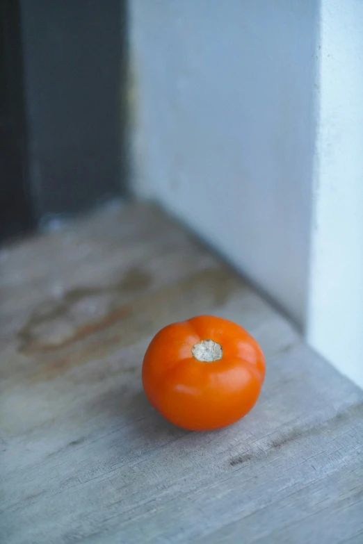 a small orange tomato sitting on top of a table