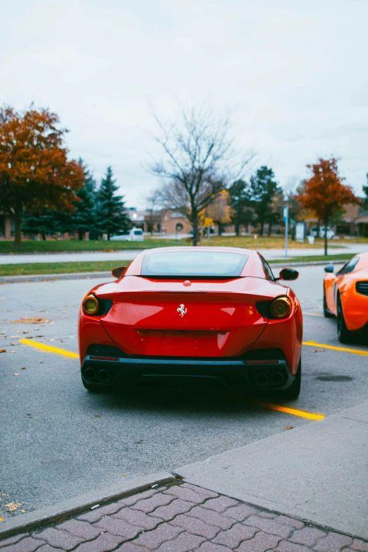 two very red sports cars parked next to each other