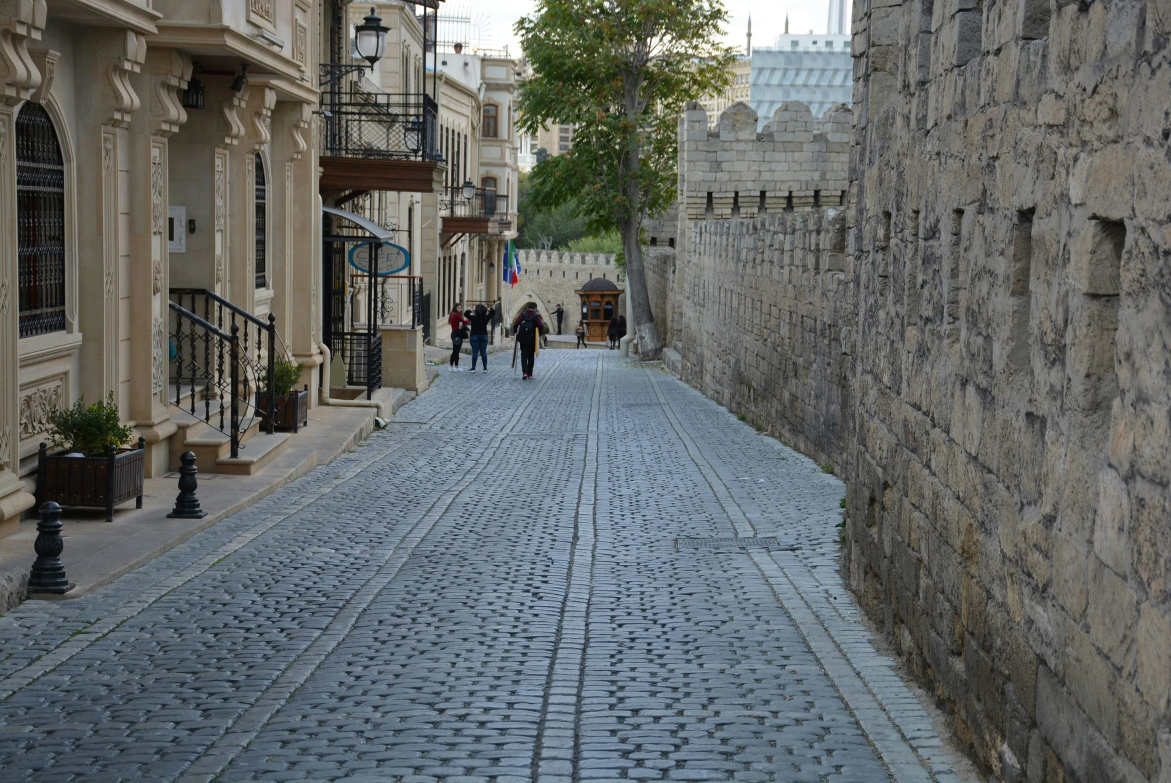 a cobblestone road that has two people walking in the background