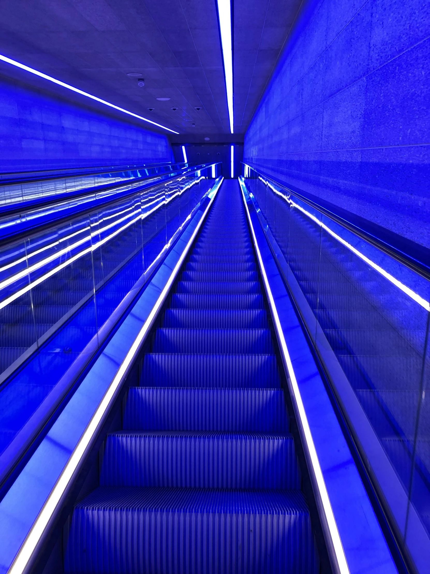 a very long blue escalator with stairs