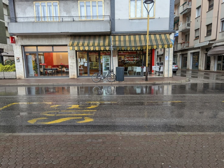 a wet street with a yellow pole on top of it