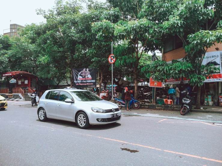 a silver car in front of a row of trees