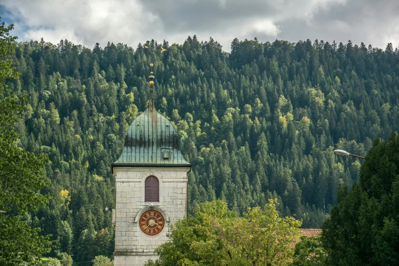 a church tower is situated in the foreground, surrounded by trees