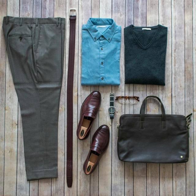 a selection of clothing, shoes and a purse lying on a wooden floor