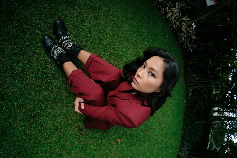 a girl in black shoes is sitting on the grass