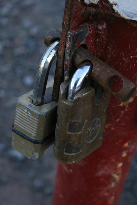 an old padlock on a red fence that is on top of concrete