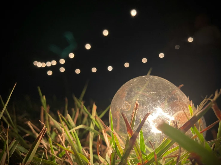 an electric lawn mower is seen in the grass next to a ball on the ground