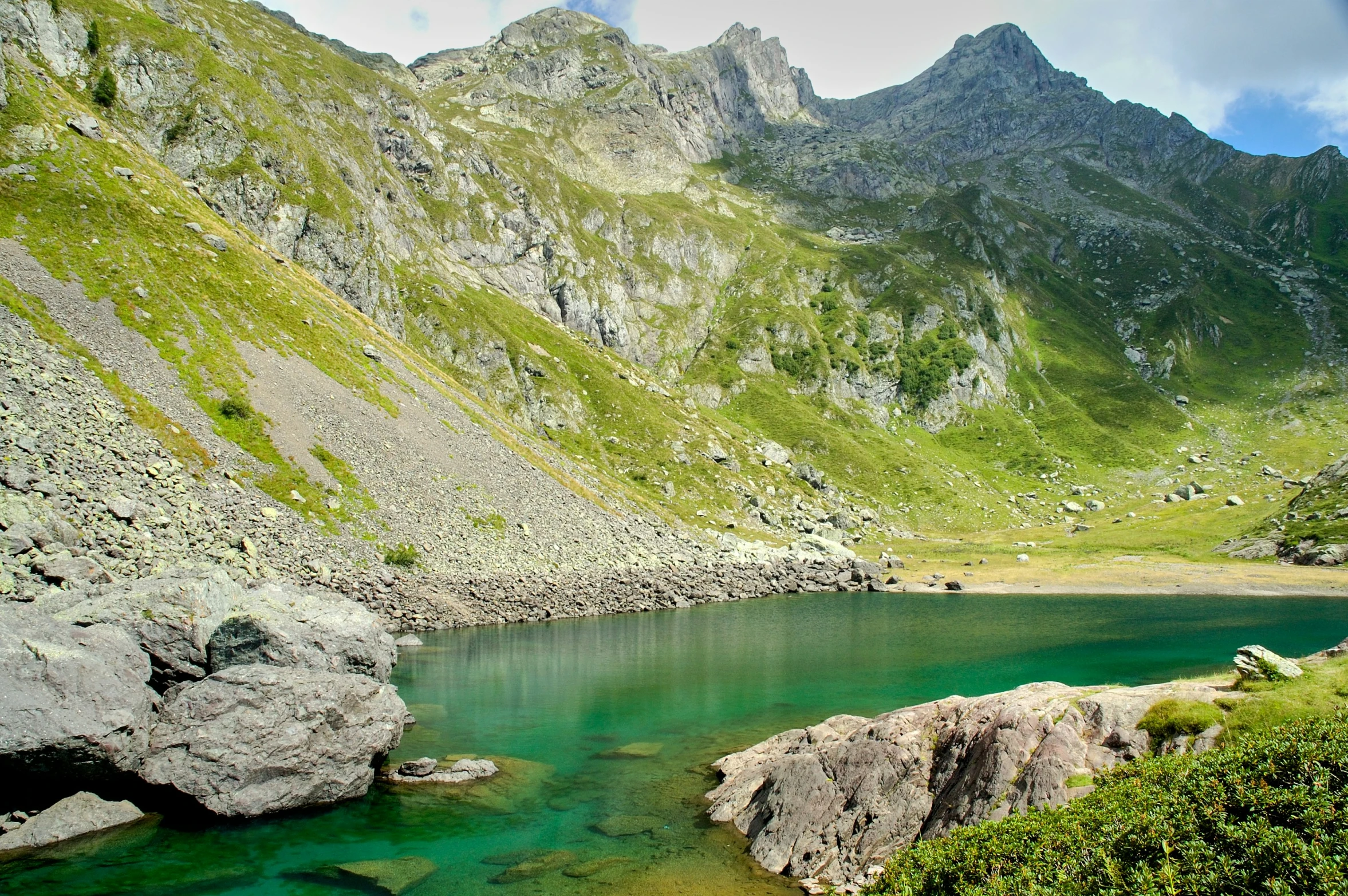 a body of water near rocks and a mountain