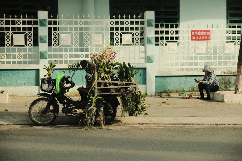 a person sitting on the sidewalk next to his motorcycle