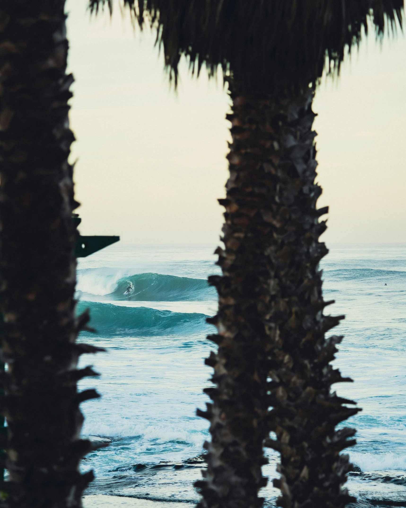 a surfboarder in the distance on top of a wave