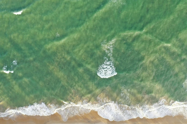 some green water and some white waves crashing on the shore