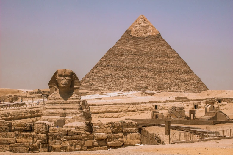 the great pyramid of giza is in the background with a statue in front