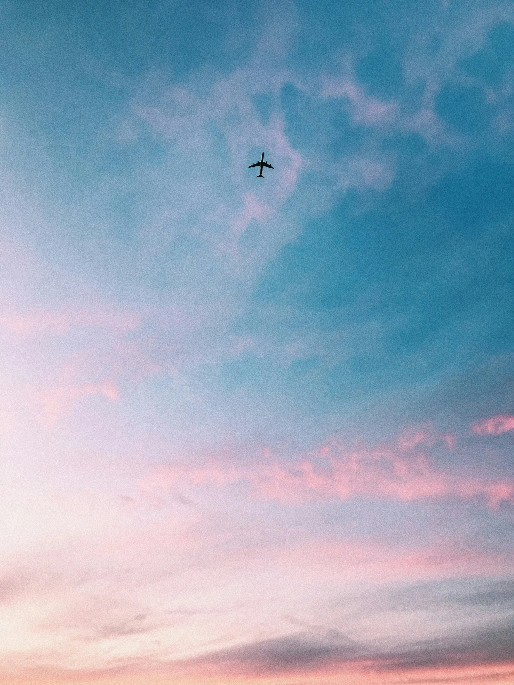 a single plane flies in the sky at sunset