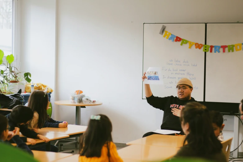 there are many students in the classroom with a man standing and raising their hands