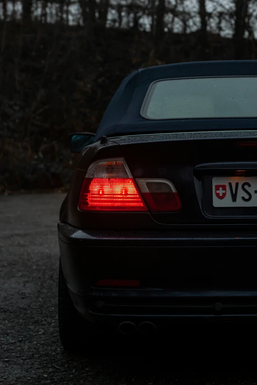 a black bmw with a red tail light