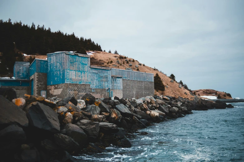 a long blue wall next to the ocean near rocky shore