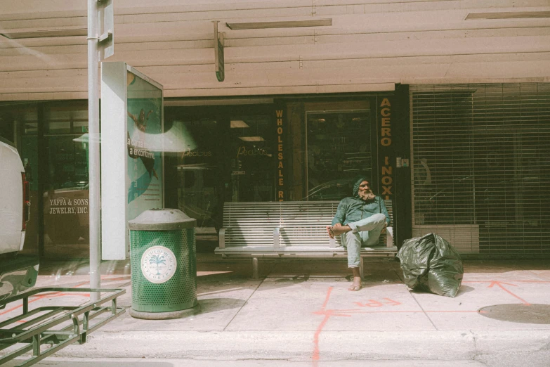 a man sitting on a bench looking down at his hand in his pocket