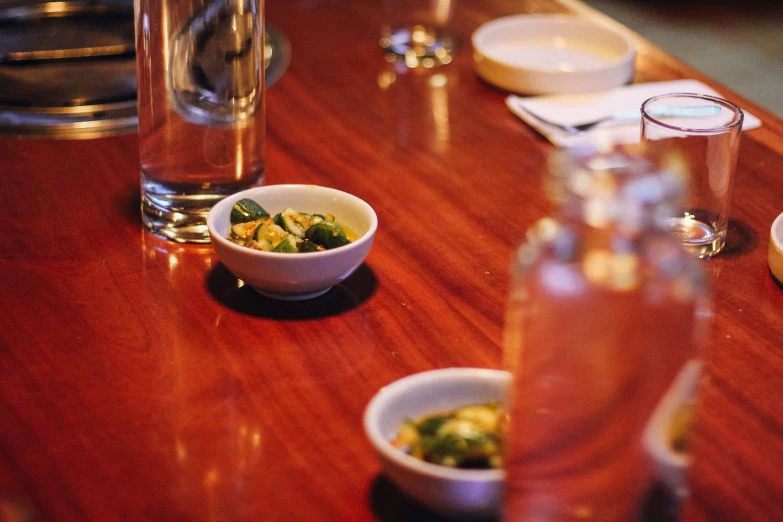 small bowls of food sit on a table with empty glasses