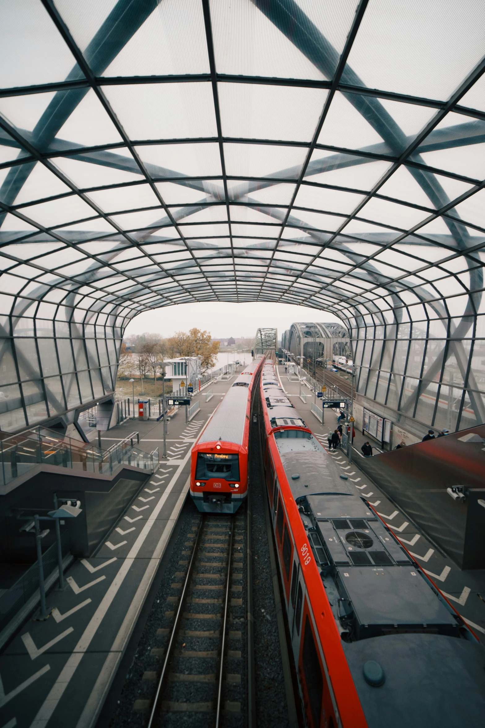 an orange train sits on the tracks under a roof