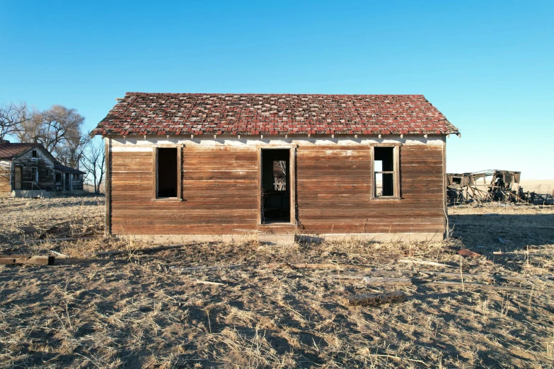 an old abandoned building with windows, covered by a red tin roof