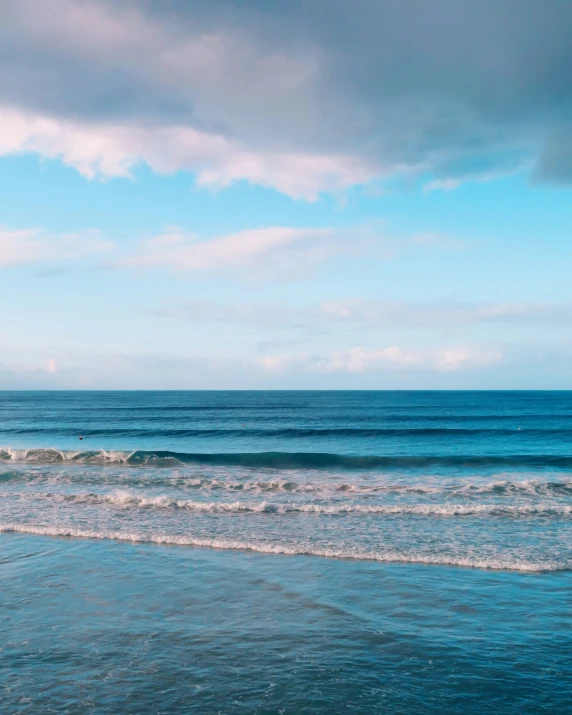 two people stand in the surf as one waves approaches