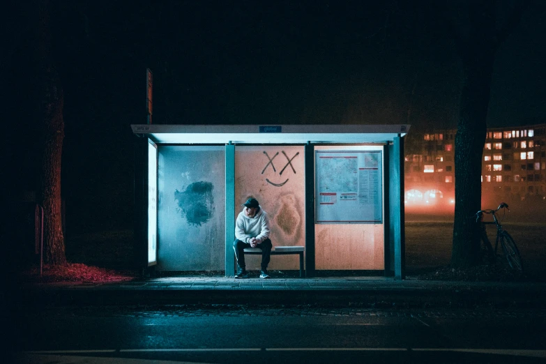 a man sitting on top of a bench in front of a bus stop