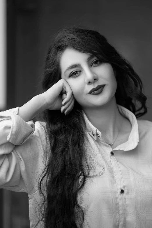 a woman with long hair leaning on a wall