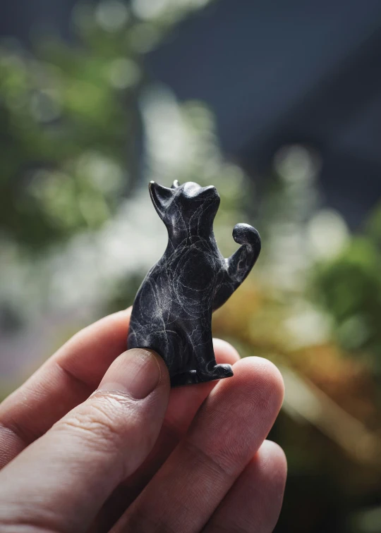 a small black bear figurine sitting on someones finger