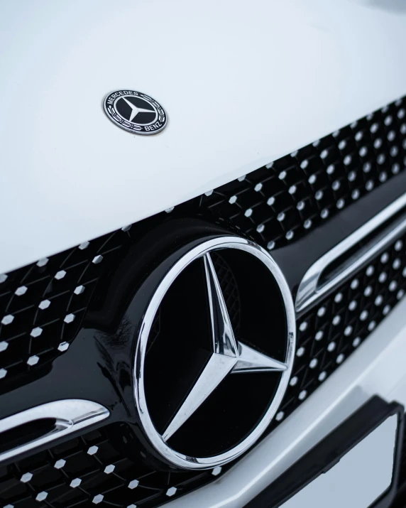 closeup s of a mercedes logo on the grille of a white car