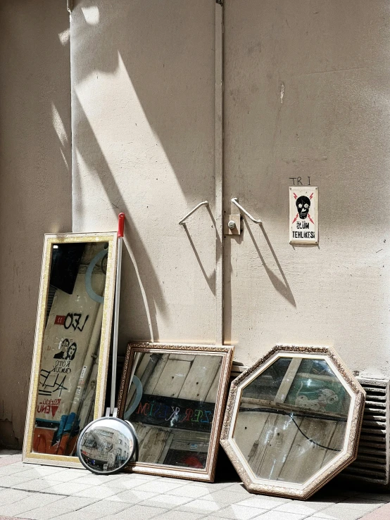 three small mirrors against a wall on the sidewalk