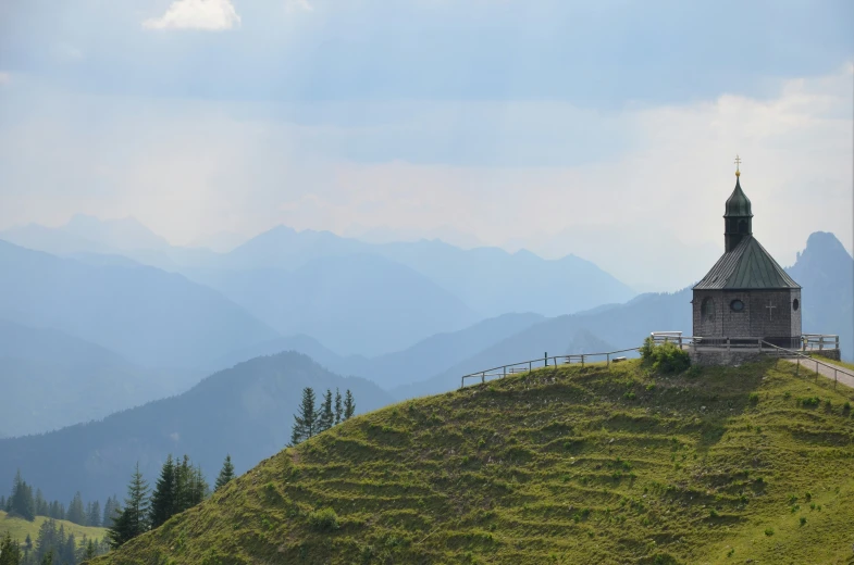 the clock tower sits on a hillside overlooking the surrounding mountain range