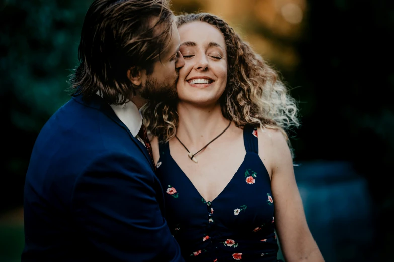 a man and woman smile as they share a kiss