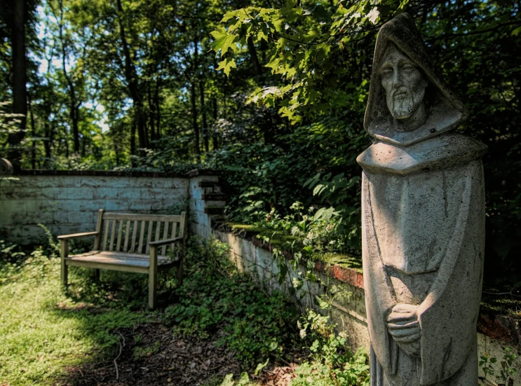 a statue and bench in an old garden