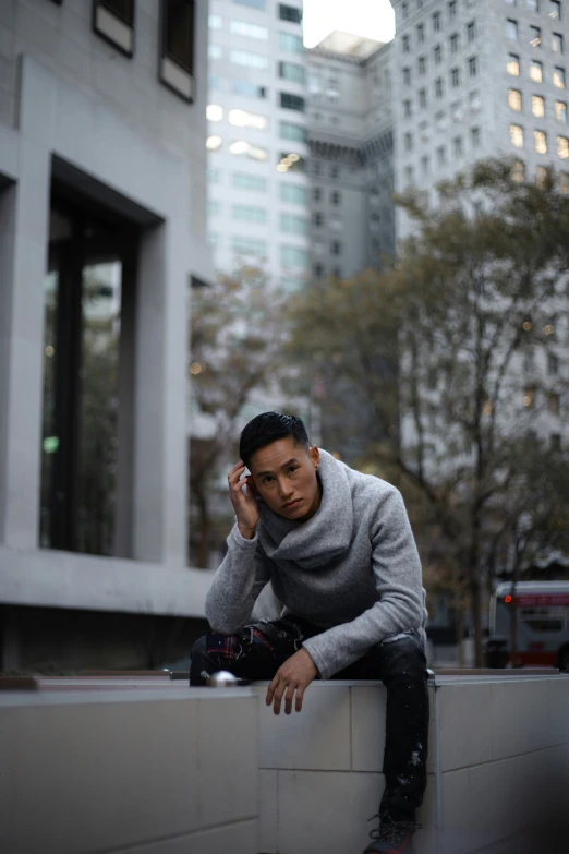 a young man talking on the phone on the side of a building