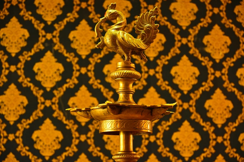 an ornate gold plated peacock motif with a wallpaper background