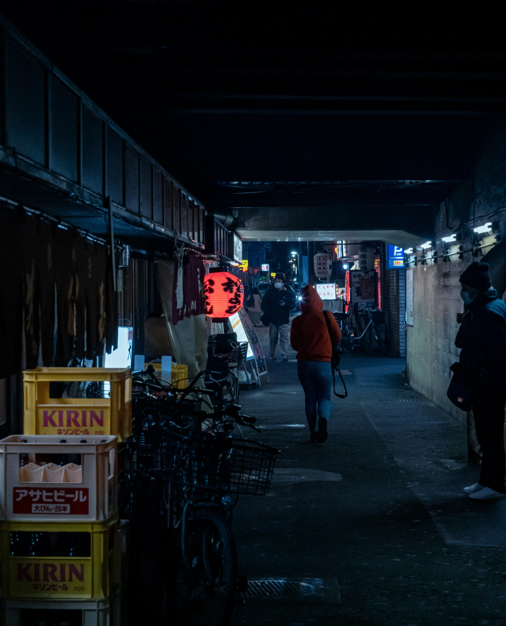 people are walking down an alley at night