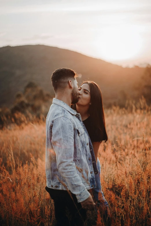 a man and woman kissing on a mountain