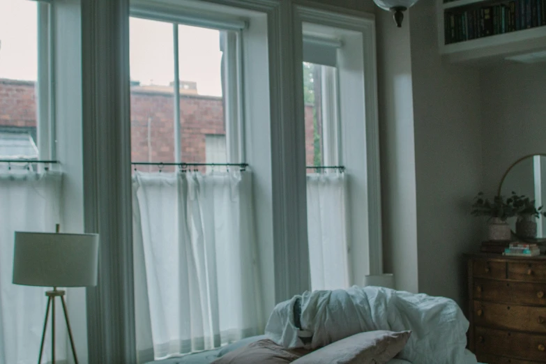 a bedroom with several windows and pillows on the bed