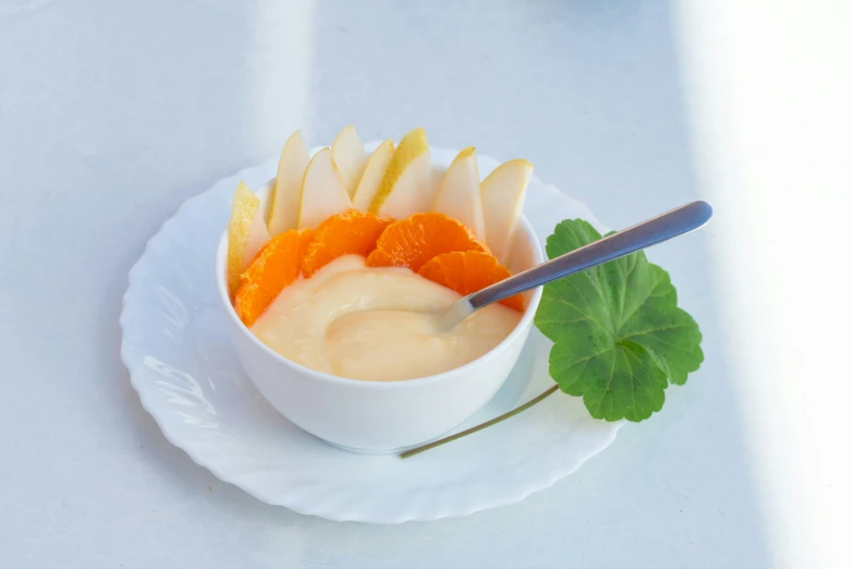 a small white bowl full of fruit with a spoon in it