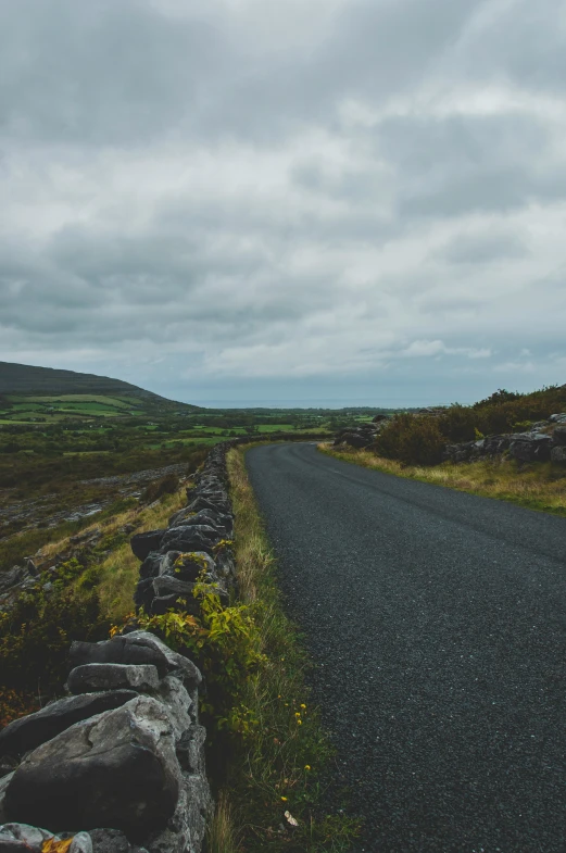 a lonely road with a few rocks in the middle