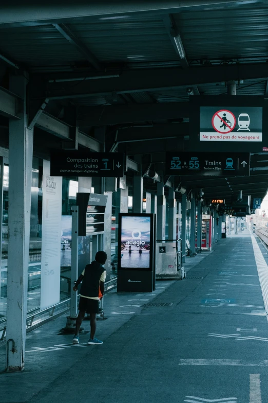 people waiting at an empty train station in dark colors