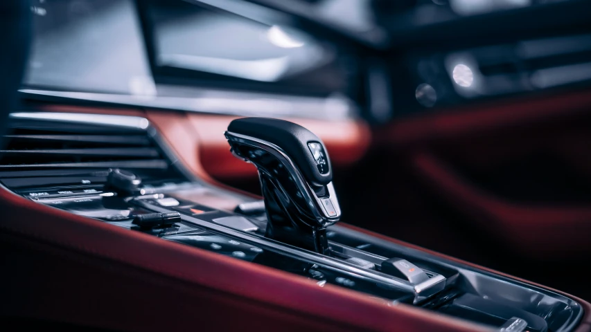 a car console with a remote control and a red leather car interior