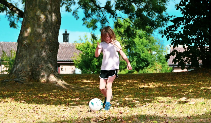 a girl kicking a soccer ball in a yard