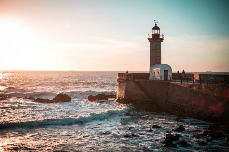 a lighthouse stands on an empty wall above the ocean