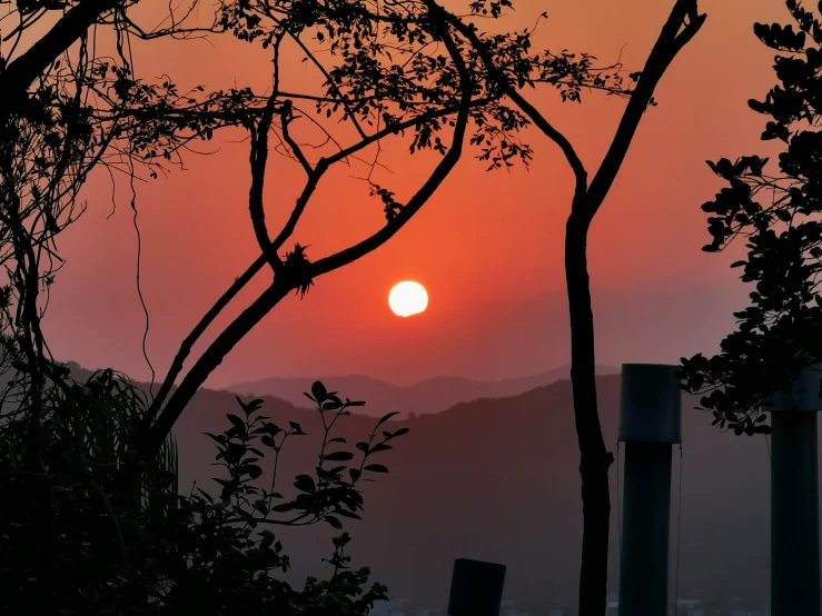 sunset in front of a mountainous area with trees