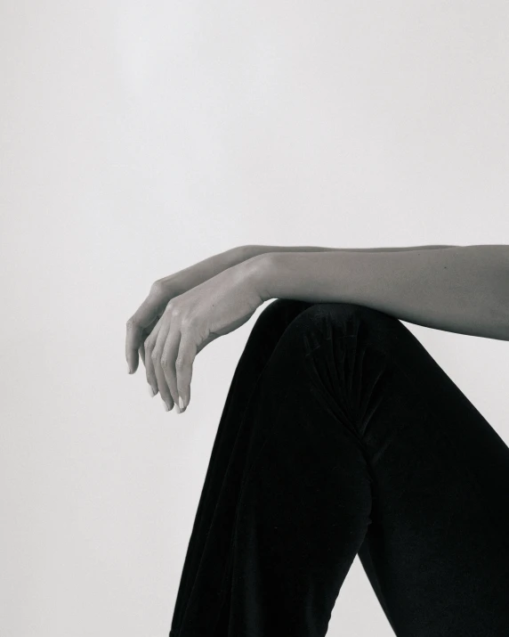 a black and white image of a woman's legs as she sits on the ground