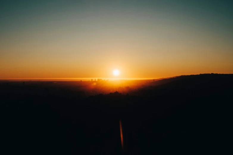 the sun rising over a hilly landscape on a nice day