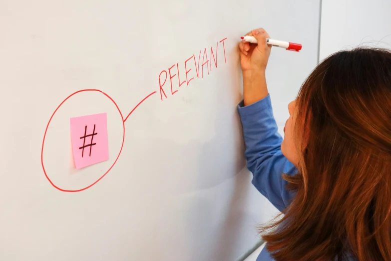 a young woman writing on a board with a marker