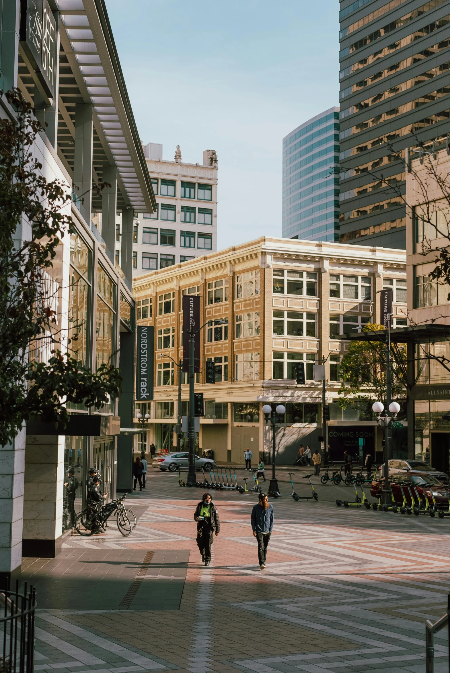 two people walking down the sidewalk past buildings